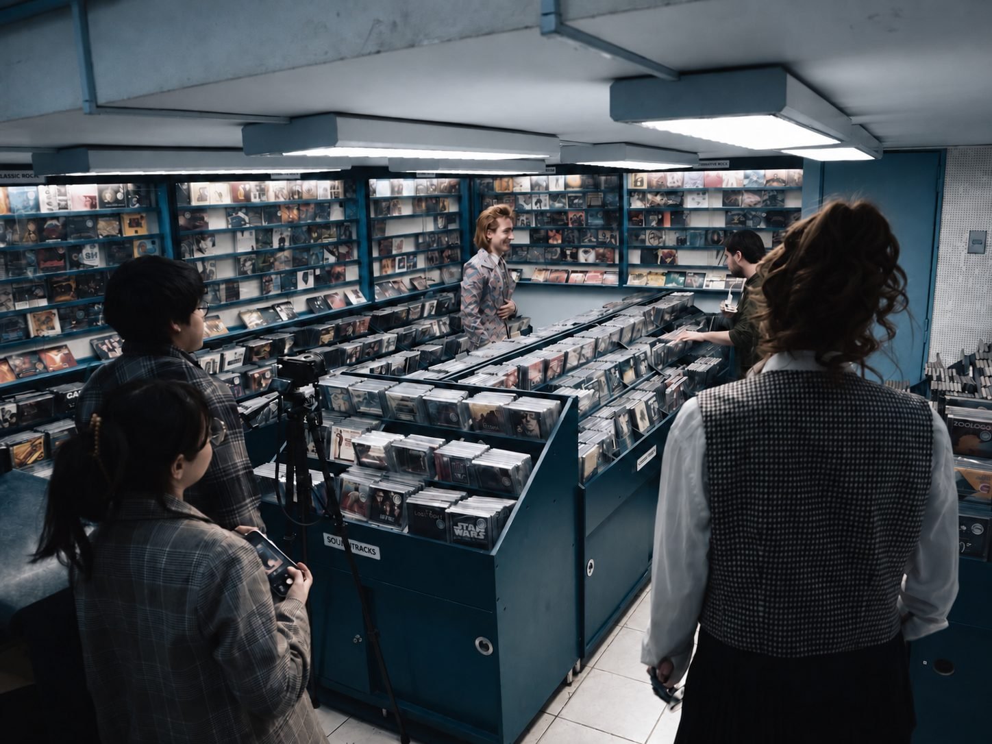 Rodaje del videoclip de «Secretaria» en una tienda de discos: Gaspar Luna al fondo entre los estantes y el equipo de cámara en primer plano